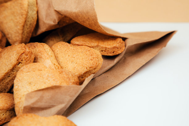 红心形状的酥饼，装在棕色纸袋里，放在白色桌子上图片下载