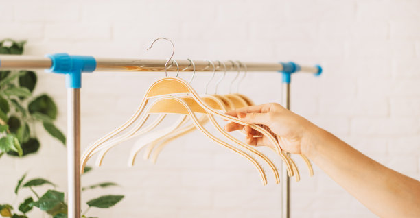 一个女人的手把一个木衣架挂在铁条上图片下载