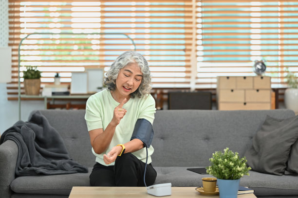 满意的老年妇女在家里用数字压力表测量血压。老年人保健概念。图片下载