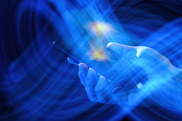 手机在一个白人男子的手中在一个黑暗的背景与抽象的光芒。图片下载