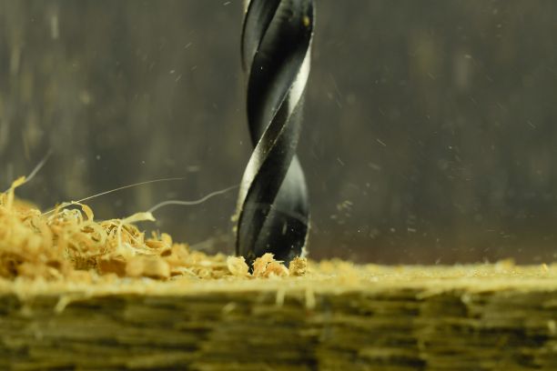 木头上的旋转钻。用飞木屑钻孔。概念为木工，工艺品，DIY。微距和特写图像图片下载