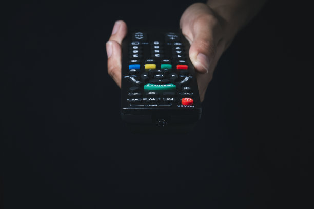 女人在黑暗中拿着电视遥控器图片下载