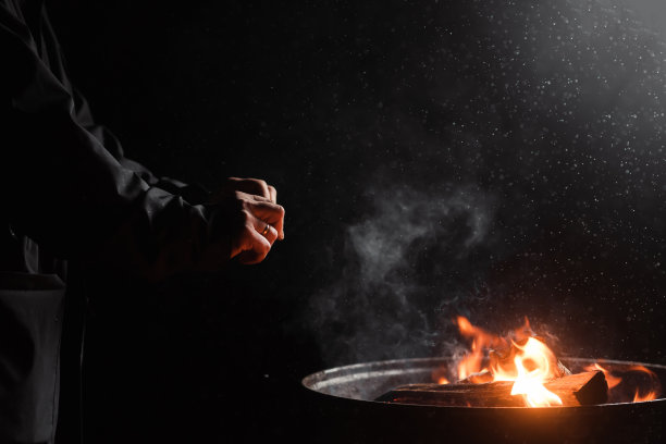 一个不认识的男人的手在黑暗中靠近一个桶的火取暖。无家可归，移民，乞丐的概念。图片下载