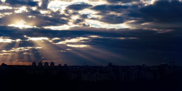 阳光透过浓密的乌云照耀着城市。图片下载