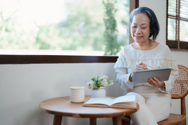 一位年长的亚洲妇女在平板电脑上工作的现代姿势的肖像。图片下载