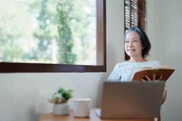 一位亚洲老妇人的现代姿势，拿着笔记本电脑，操作着电脑。图片下载