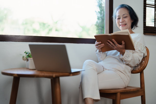 一位亚洲老妇人的现代姿势，拿着笔记本电脑，操作着电脑。图片下载