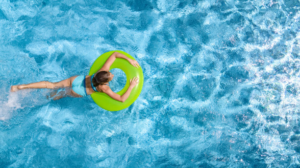 活跃的年轻女孩在游泳池空中俯瞰上方，青少年放松和游泳在充气环甜甜圈，并在家庭度假，热带度假胜地的水里玩得很开心图片下载