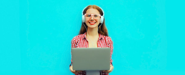 现代年轻女子的肖像与笔记本电脑听音乐在蓝色背景耳机图片下载