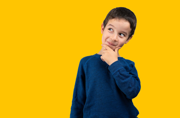 淘气的小男孩斜视着黄色背景图片下载