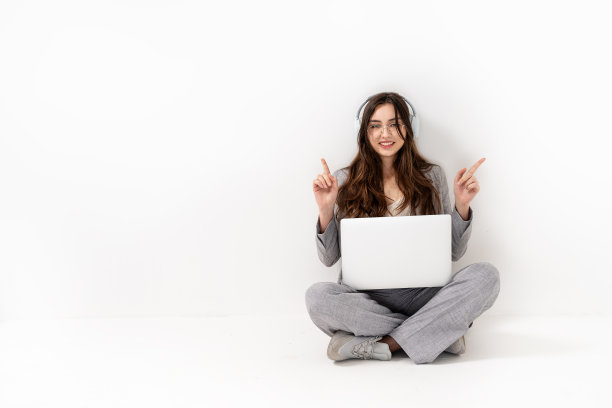 年轻快乐的微笑白人女孩戴着耳机学习在线聊天会议使用笔记本电脑。影棚拍摄。图片下载