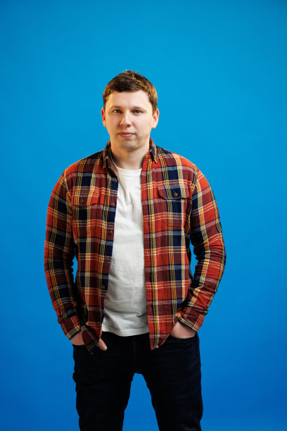 肖像英俊的欧洲男子在衬衫看着相机站在蓝色的工作室背景图片下载