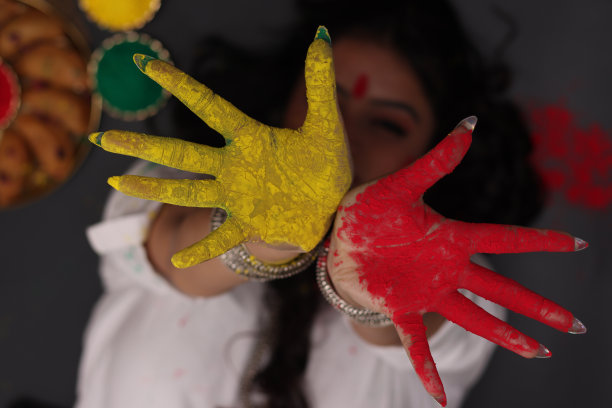 一个美丽的女人女孩女士躺下摆姿势庆祝胡里节的颜色看向镜头外的Abeer gulal干色粉和印度甜Gujiya pedukiya kashew图片下载