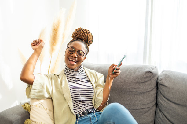 微笑的非裔美国妇女在家里听音乐图片下载