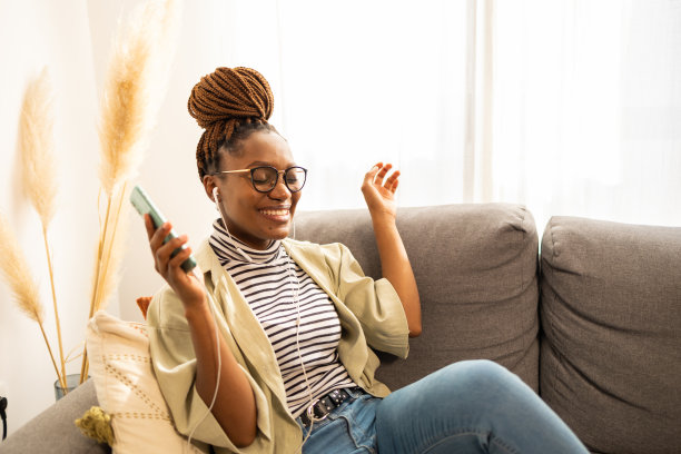 微笑的非裔美国妇女在家里听音乐图片下载