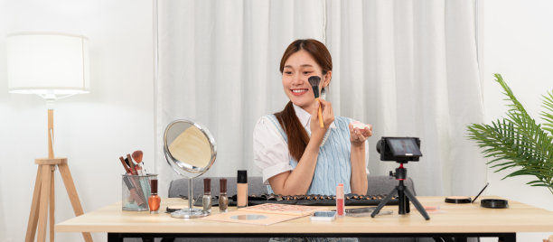 年轻的美妆网红正在用刷子在脸颊上涂抹腮红，测试并推荐化妆品图片下载