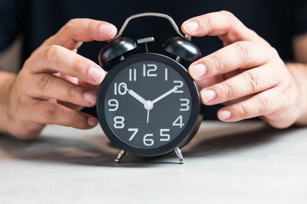 男人的手拿着黑色闹钟图片下载