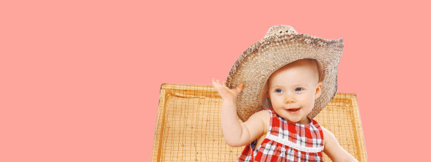 孩子的肖像在草帽夏天坐在手提箱上看着粉红色的背景图片下载