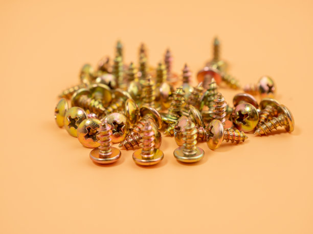 用于拧入塑料的螺丝。橙色背景上的金属螺丝。图片下载