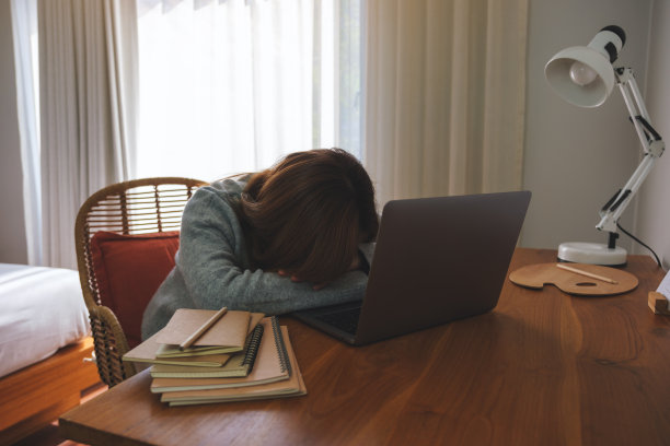 一名年轻女子在家里用笔记本电脑工作时累了，在办公桌前睡着了图片下载