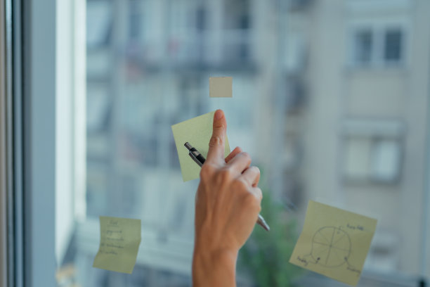 女人在家庭办公室的玻璃上的便利贴上写下自己的想法图片下载