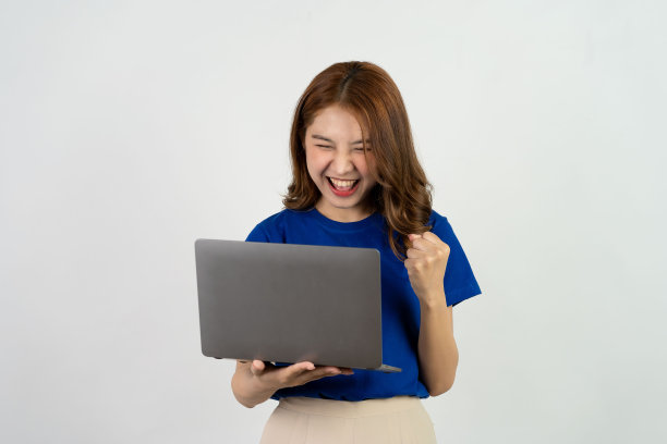 可爱的亚洲少女笑得很开心，兴奋地用白色背景的电脑工作图片下载