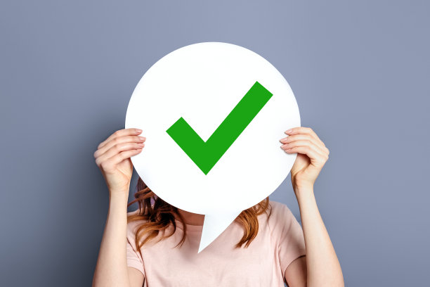 女孩拿着一张海报，上面写着“是”，孤立在灰色背景上图片下载