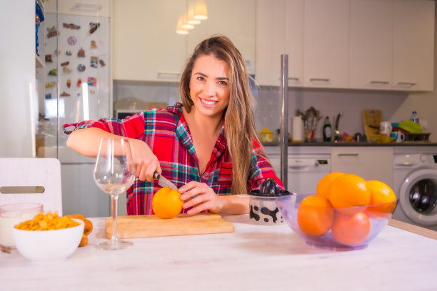 金发西班牙女人在她的厨房做橙汁早餐图片下载