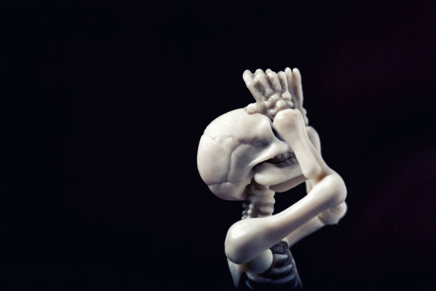 骷髅雕像以黑色背景支撑头部。压力，悲伤，精神问题，沮丧，失望，绝望的概念图片下载