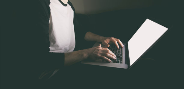 晚上，年轻人坐在沙发上，拿着现代的笔记本电脑上网图片下载