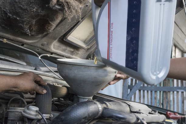 汽车机械师改变和注入新鲜的油到发动机-库存照片图片下载