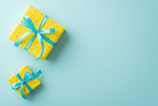 复活节的概念。顶视图照片亮黄色的礼品盒与蓝色缎带蝴蝶结孤立的淡蓝色背景与空白图片下载