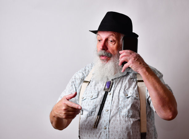 年长的白人大胡子男子正在他的手机上严肃地交谈图片下载