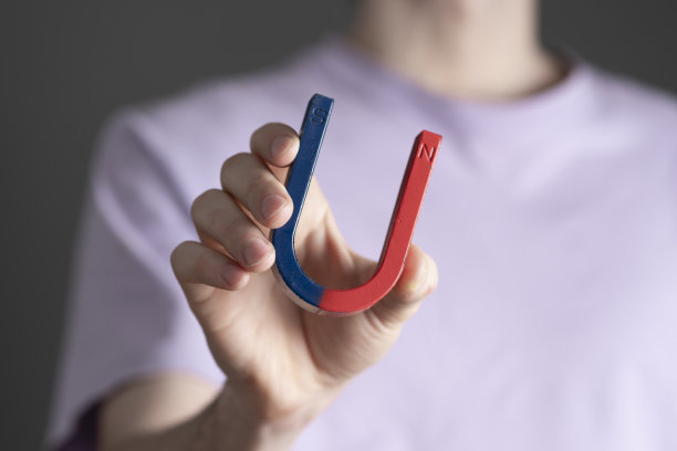 学生拿着马蹄形的蓝色和红色磁铁，做科学测试图片下载