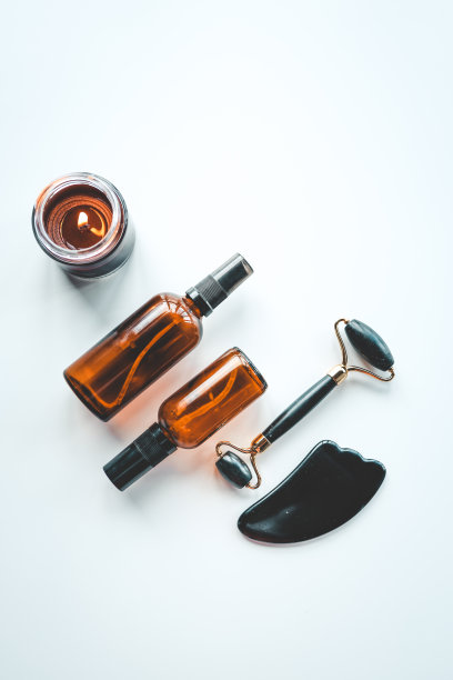 豪华护肤化妆品套装。平铺黑脸辊，罐或保湿霜，瓜沙，蜡烛，精华液在石桌上图片下载