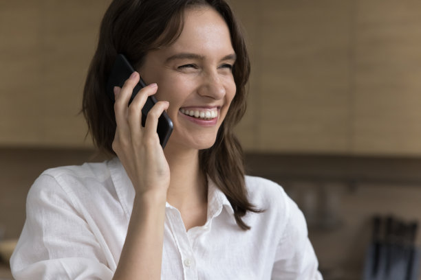 快乐的年轻自由职业者妇女在家里打电话图片下载