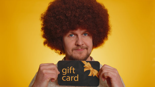 年轻快乐的男子显示指向礼品折扣证书代金券优惠券商店节日销售图片下载