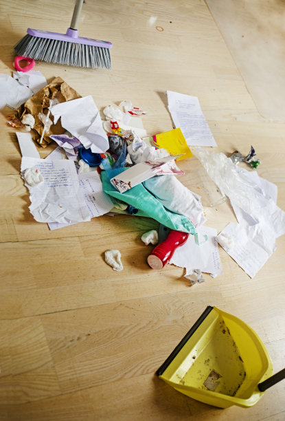 一个十几岁的女孩用扫帚和簸箕在拼花地板上垂直地清理她房间里的垃圾图片下载