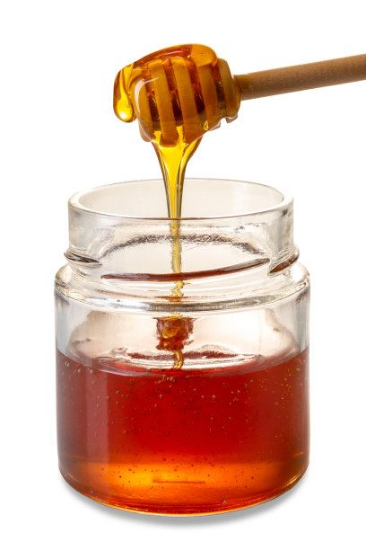 蜂蜜从玻璃罐中的木制蜂蜜勺滴下图片下载