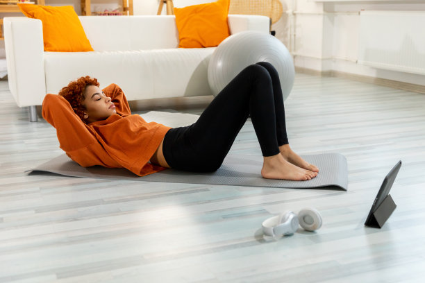 健身训练。年轻健康适合非洲女孩做自行车紧缩腹肌锻炼在地板上的瑜伽垫在家里。穿着运动服的女运动员正在练腹肌。运动和健身。图片下载