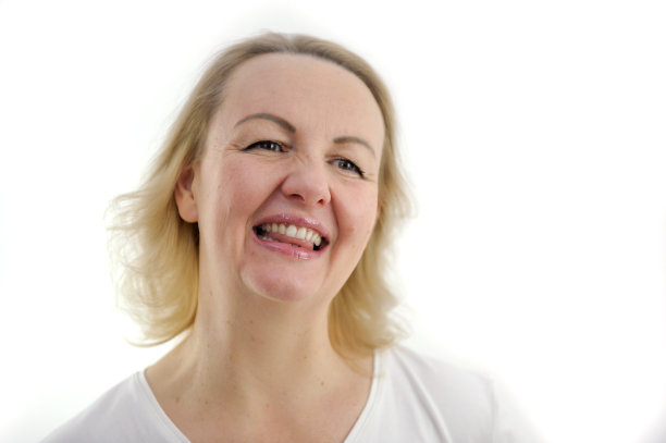 真诚的微笑，一个美丽的女人发光的眼睛，近距离的脸在一个白色的背景上，牙齿半开，舌头是可见的喜悦柔情女性美丽柔情魅力中年金发图片下载