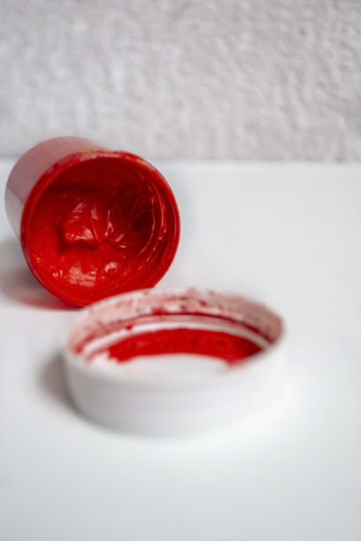 白色的桌子上放着红色的水彩画。一罐倒装的红色水彩画。一罐开着漆的红色水彩。图片下载