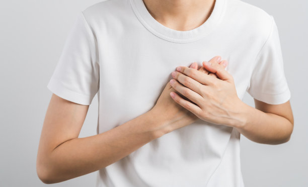 由于心脏病发作的症状，女子在白色背景上疼痛，将手按在胸部。保健和医疗概念。图片下载