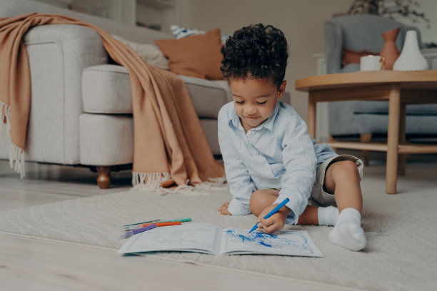 可爱的非洲孩子坐在地板上画画，在家里玩图片下载