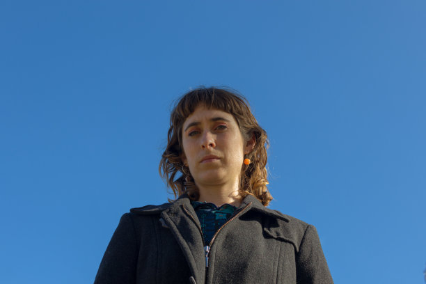 一个绿色的眼睛阿根廷妇女看着相机与蓝色晴朗的天空在她身后图片下载