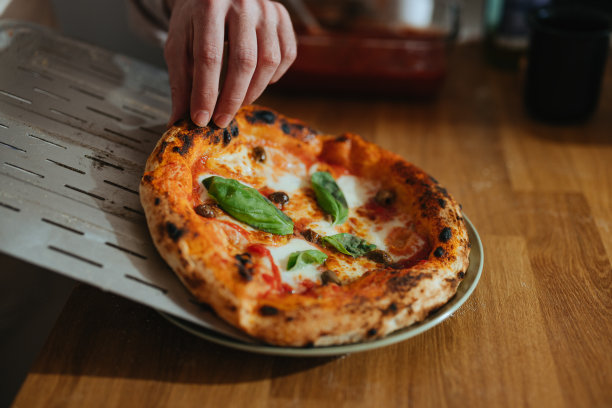 近距离的照片，男子的手端玛格丽特披萨在盘子里图片下载