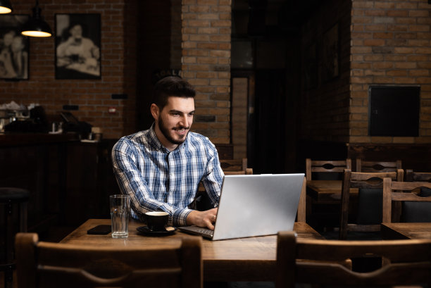 在一家舒适的酒吧和自助餐厅，年轻的商人老板或经理下班后坐在那里，用笔记本电脑控制着收入和营业额，为第二天做好一切准备图片下载