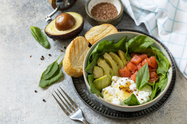 经典的早餐，早午餐——水煮蛋，牛油果，芝麻菜，亚麻籽和盐腌鲑鱼在灰色的背景上。副本的空间。图片下载