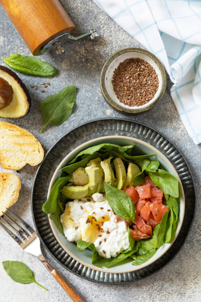 经典的早餐，早午餐——水煮蛋，牛油果，芝麻菜，亚麻籽和盐腌鲑鱼在灰色的背景上。从上面看。图片下载