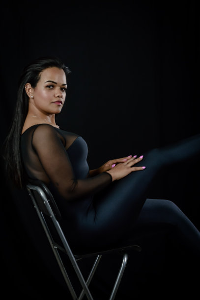 一个美丽的年轻巴西女子坐在凳子上，穿着紧身的身体套装的肖像图片下载